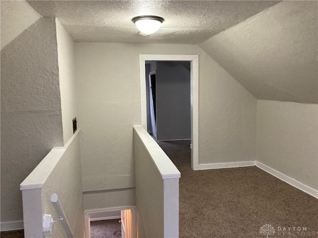 stairway with lofted ceiling, a textured wall, carpet flooring, a textured ceiling, and baseboards