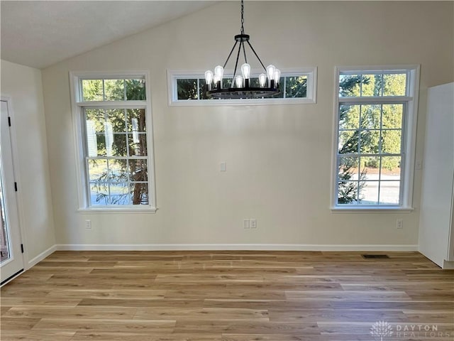 unfurnished dining area with lofted ceiling, baseboards, light wood-style flooring, and a notable chandelier