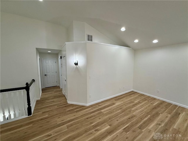 empty room with baseboards, visible vents, lofted ceiling, wood finished floors, and recessed lighting