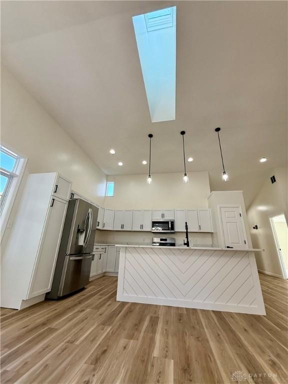 kitchen featuring stainless steel appliances, light wood finished floors, a large island, and white cabinets