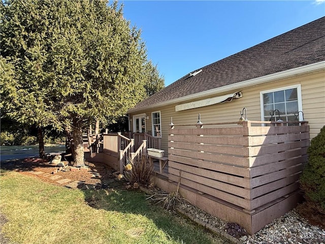 view of property exterior featuring a shingled roof, a lawn, and a wooden deck