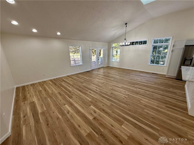 unfurnished dining area featuring a wealth of natural light, lofted ceiling, baseboards, and wood finished floors