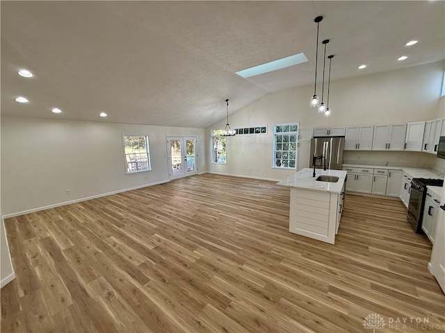 kitchen with black gas range, a sink, open floor plan, stainless steel fridge with ice dispenser, and a center island with sink