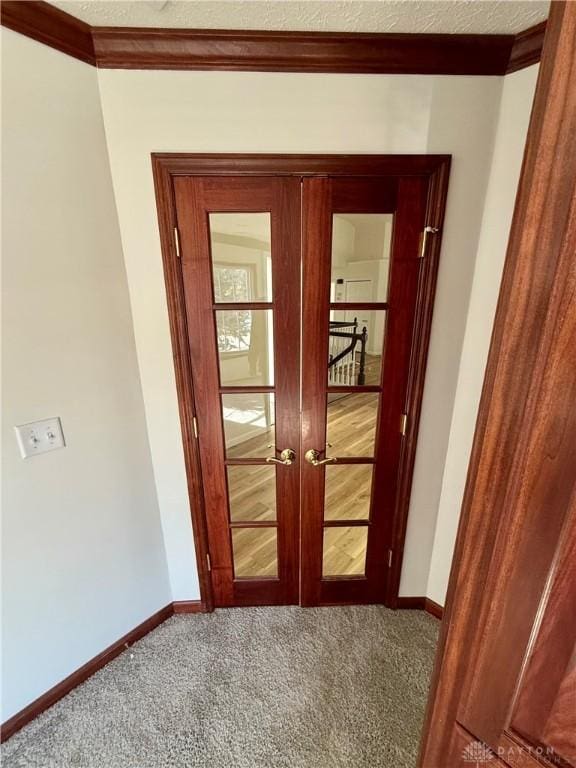 interior space featuring carpet floors, french doors, ornamental molding, a textured ceiling, and baseboards