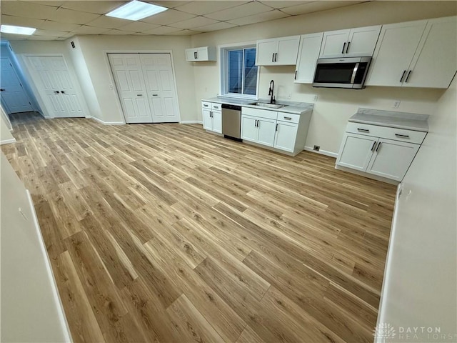 kitchen featuring stainless steel appliances, light wood-type flooring, a drop ceiling, and a sink