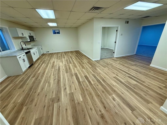 finished below grade area with light wood-style flooring, visible vents, baseboards, and a drop ceiling