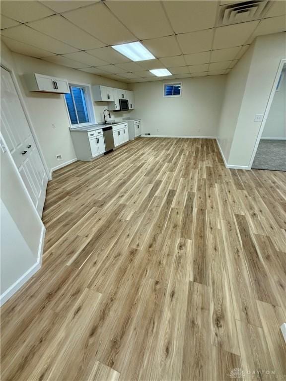 interior space featuring light wood-type flooring, visible vents, a sink, and a drop ceiling