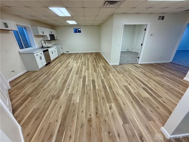 interior space featuring visible vents, open floor plan, white cabinetry, a sink, and dishwasher