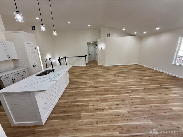 kitchen with recessed lighting, hanging light fixtures, light wood-style flooring, white cabinets, and a sink