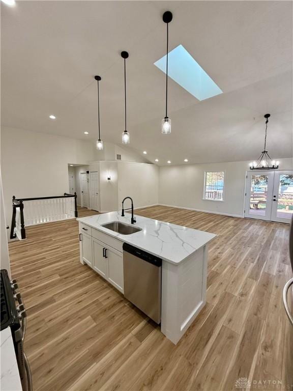 kitchen featuring white cabinets, open floor plan, stainless steel appliances, light wood-style floors, and a sink