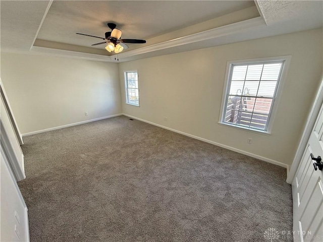 unfurnished bedroom featuring baseboards, a tray ceiling, and dark carpet