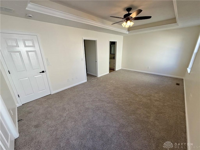 unfurnished bedroom with visible vents, baseboards, a raised ceiling, ornamental molding, and carpet