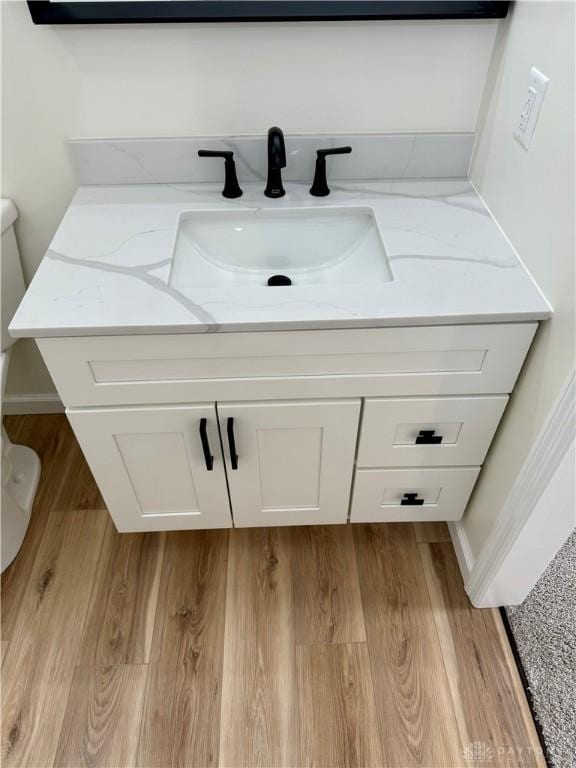 bathroom featuring toilet, wood finished floors, and vanity