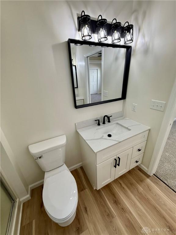 bathroom with toilet, baseboards, and wood finished floors