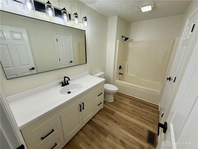 bathroom featuring visible vents, toilet, wood finished floors, a textured ceiling, and vanity