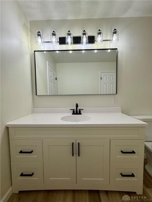 bathroom with a textured ceiling, wood finished floors, and vanity