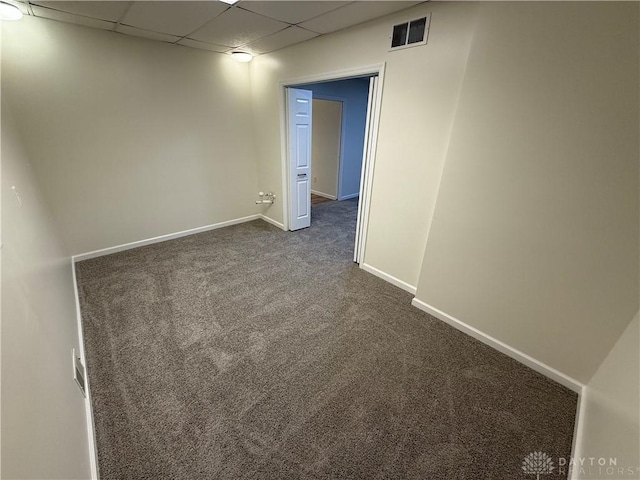 empty room featuring baseboards, visible vents, dark carpet, and a drop ceiling