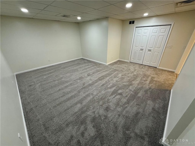 finished basement with baseboards, visible vents, and carpet flooring