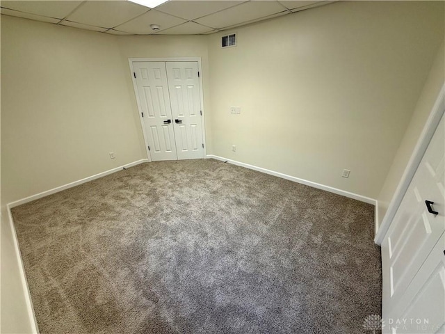 interior space featuring a drop ceiling, carpet, visible vents, and baseboards