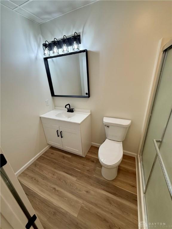 bathroom featuring toilet, baseboards, wood finished floors, and vanity