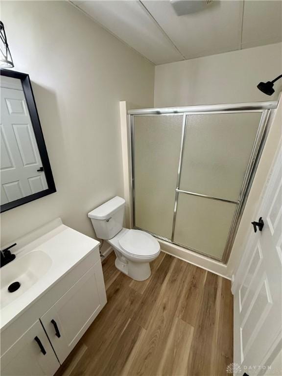 bathroom featuring toilet, a shower stall, wood finished floors, and vanity