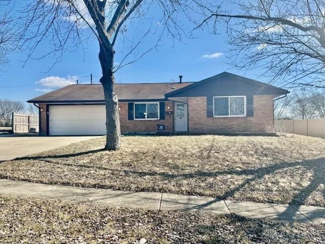 ranch-style home featuring a garage, driveway, brick siding, and fence