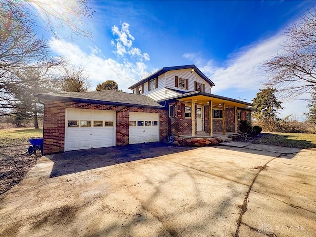 view of front of property featuring covered porch, driveway, brick siding, and an attached garage