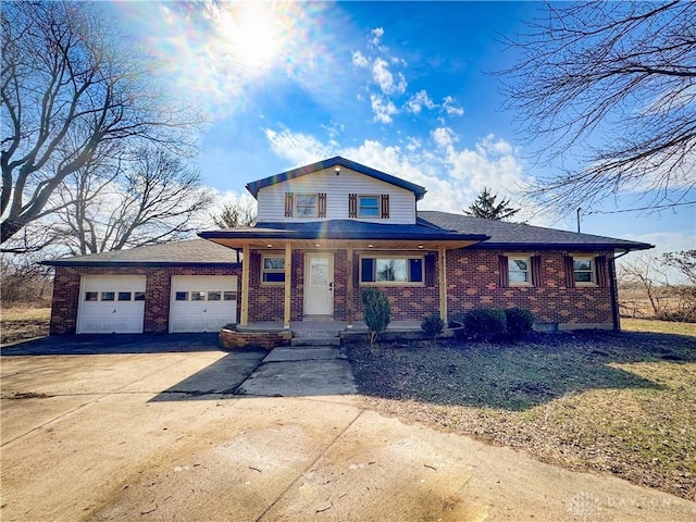 view of front of house featuring a garage, concrete driveway, brick siding, and covered porch