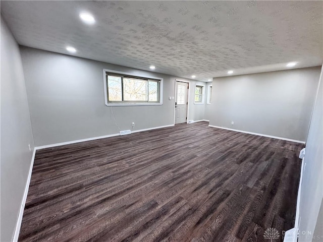 below grade area featuring dark wood-style floors, a textured ceiling, recessed lighting, and baseboards