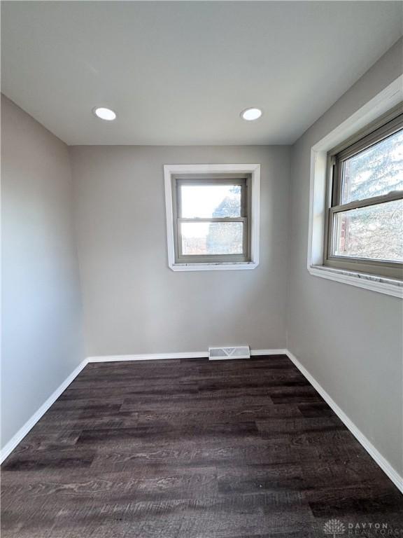 empty room with dark wood-type flooring, recessed lighting, visible vents, and baseboards