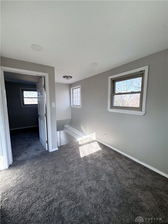 unfurnished room featuring carpet, plenty of natural light, and baseboards