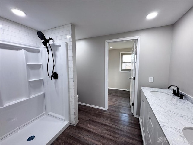 full bathroom with wood finished floors, a sink, a shower stall, and double vanity