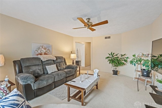 carpeted living area with ceiling fan, visible vents, and a textured ceiling