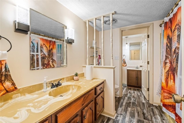 bathroom with visible vents, toilet, wood finished floors, a textured ceiling, and vanity