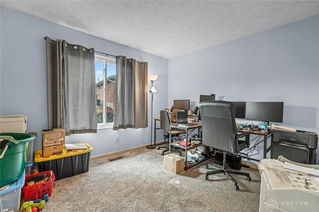 office with baseboards, visible vents, a textured ceiling, and carpet flooring