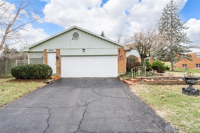 ranch-style house featuring an attached garage, fence, aphalt driveway, and brick siding