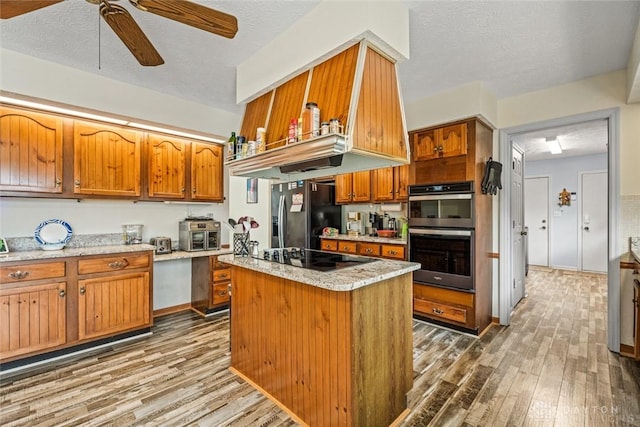 kitchen featuring black appliances, light wood-style flooring, and brown cabinets