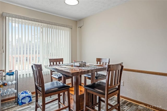 dining area featuring plenty of natural light, a textured ceiling, baseboards, and wood finished floors