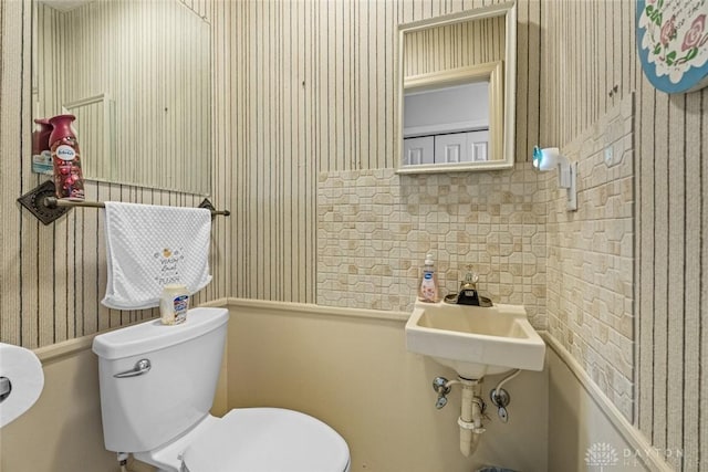 half bath featuring toilet and wallpapered walls