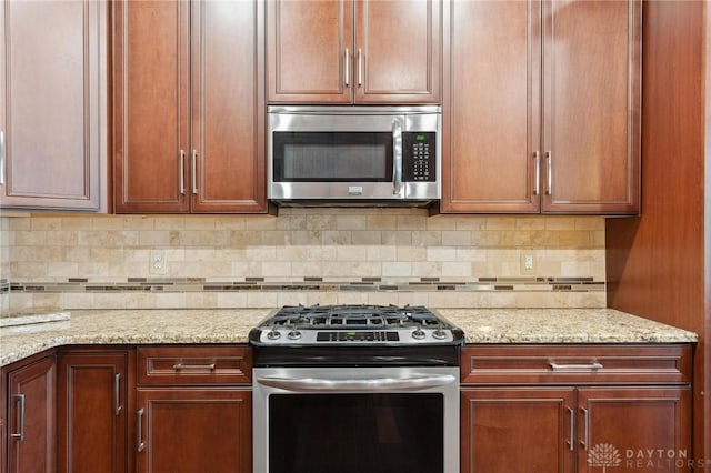 kitchen with appliances with stainless steel finishes, light stone counters, and backsplash