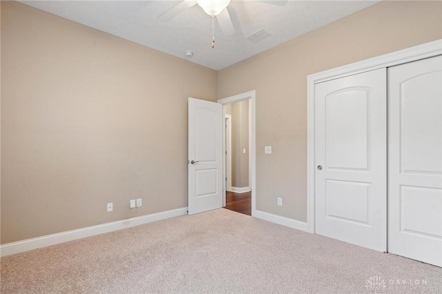 unfurnished bedroom with a closet, carpet, a ceiling fan, and baseboards