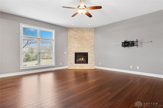 unfurnished living room with baseboards, a fireplace, hardwood / wood-style floors, and ceiling fan