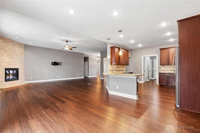 kitchen featuring open floor plan, a peninsula, a fireplace, and dark wood-style floors