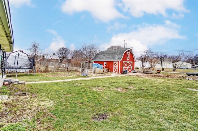 view of yard featuring a barn, a garage, a trampoline, and an outdoor structure