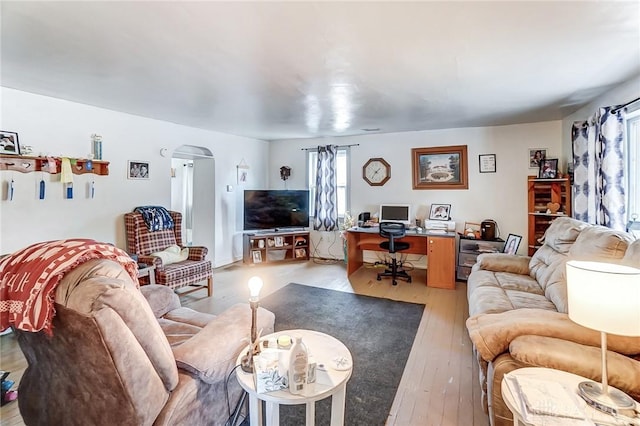 living area featuring arched walkways and light wood finished floors