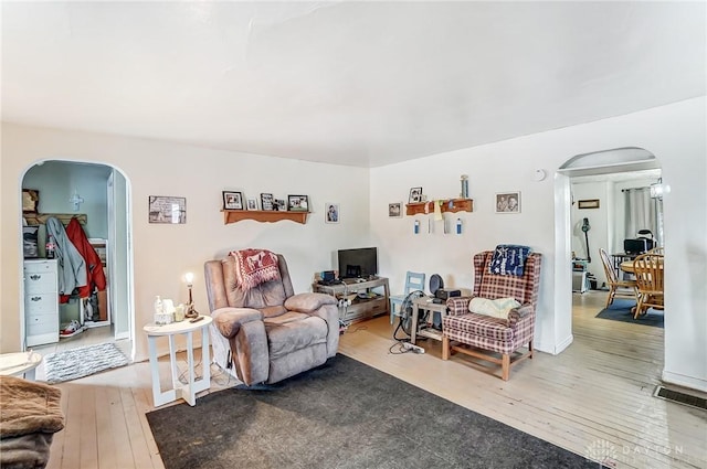 living room featuring visible vents, arched walkways, and hardwood / wood-style floors