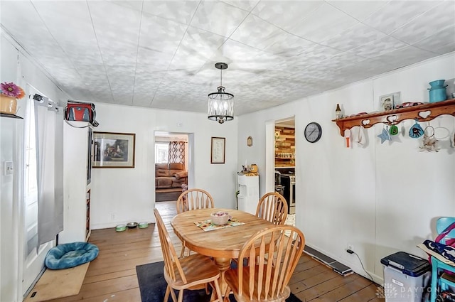 dining room with a notable chandelier, baseboards, and hardwood / wood-style floors