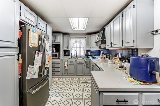 kitchen featuring gray cabinetry, a sink, light countertops, appliances with stainless steel finishes, and tasteful backsplash