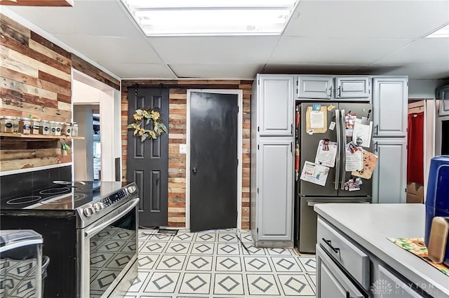 kitchen with white cabinets, wood walls, stainless steel appliances, and light countertops