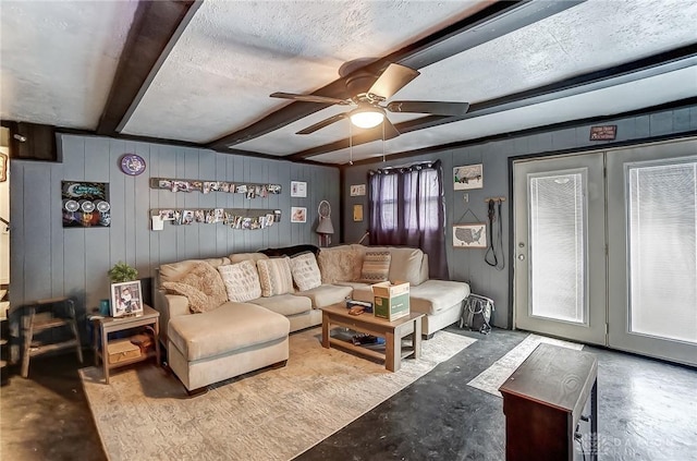 living area featuring a ceiling fan, concrete flooring, beamed ceiling, and a textured ceiling